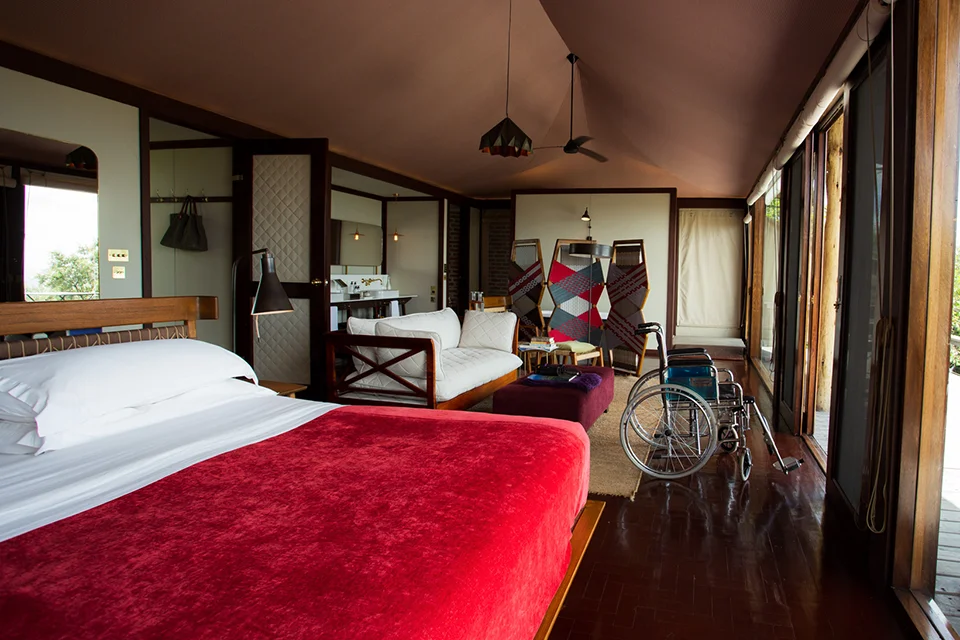 Wheelchair-accessible guest suite with a spacious bedroom, lounge area and wide glass doors at a safari lodge