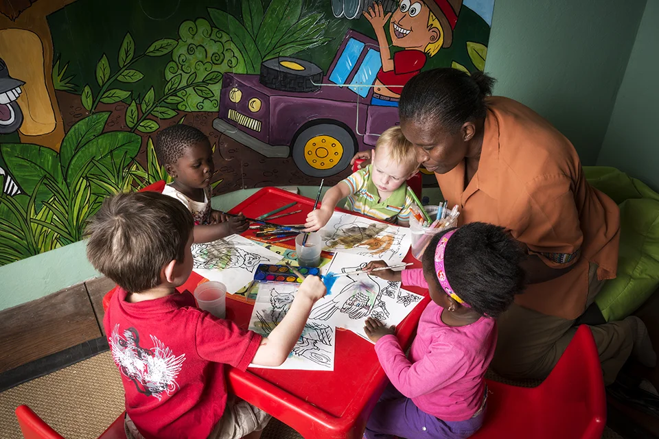 Children paint and colour pictures together during a supervised indoor activity