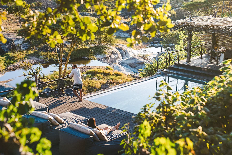 Guests relaxing beside the infinity pool at a luxury safari lodge in the Greater Serengeti ecosystem
