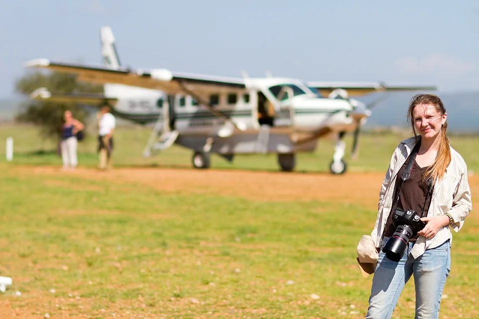Woman standing beside a light aircraft at a remote safari airstrip