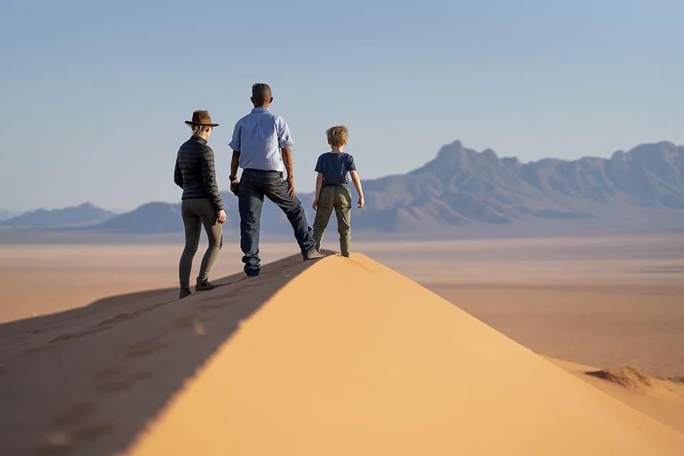 Family exploring a sand dune at Kwessi Dunes in the NamibRand Nature Reserve, Namibia