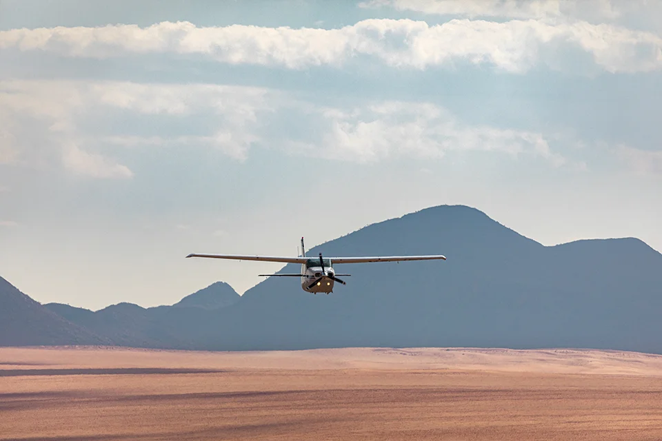 Light aircraft flying over the desert landscape near Kwessi Dunes in Namibia