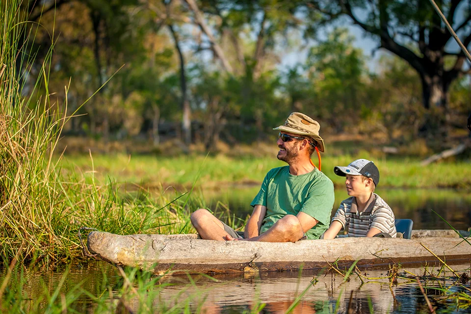 Father and son exploring the Okavango Delta by mokoro near Oddballs’ Camp, Botswana