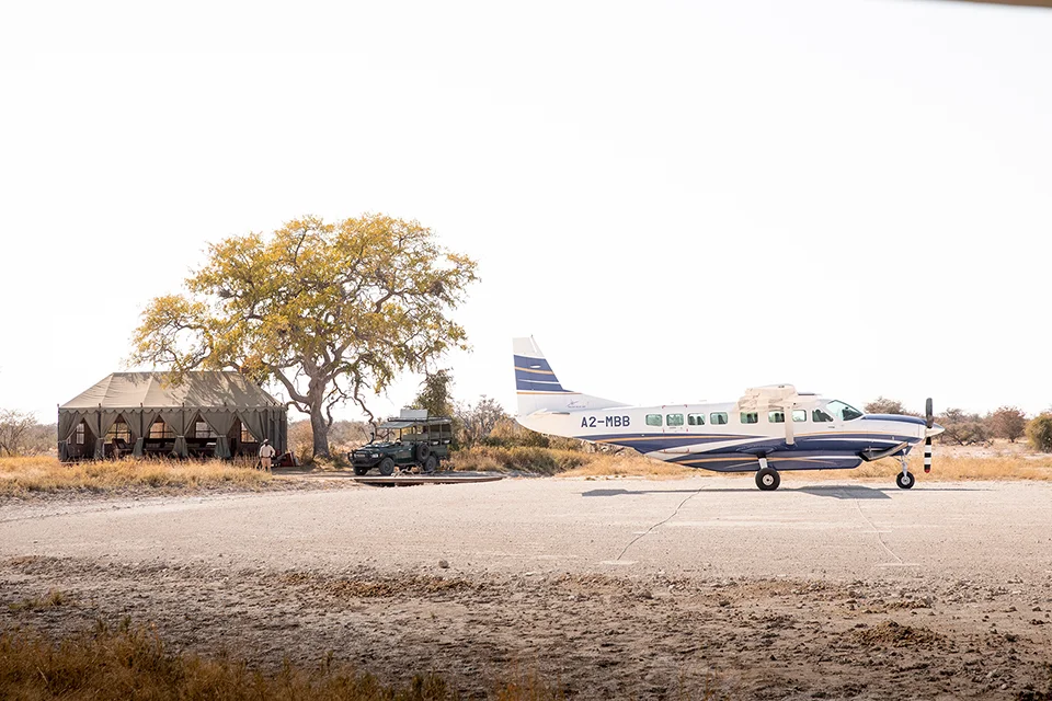 Light aircraft parked at a safari airstrip beside a luxury tented camp in Botswana