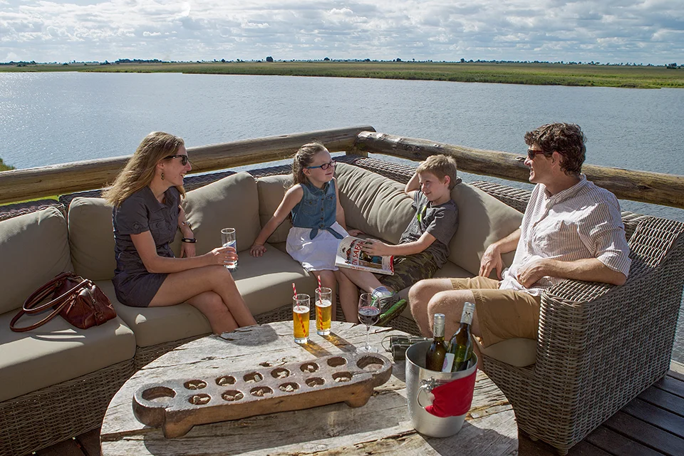 Family relaxing on a riverside lodge deck overlooking the Chobe River