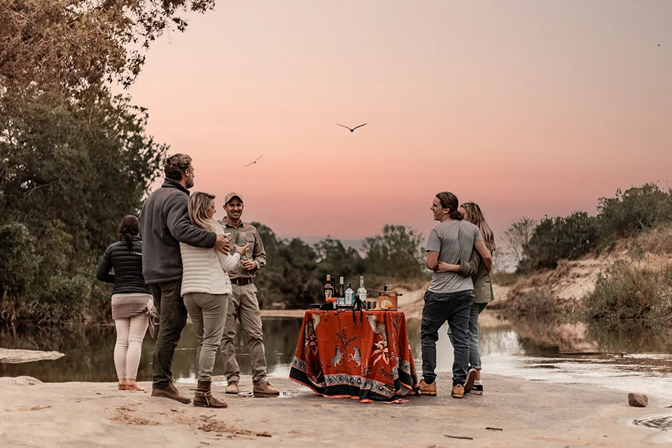 Guests enjoying sundowners beside a river at Dulini Moya in the Sabi Sand Nature Reserve, South Africa