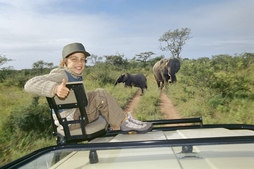 Child enjoying a family safari as elephants cross the track in Botswana's Okavango Delta