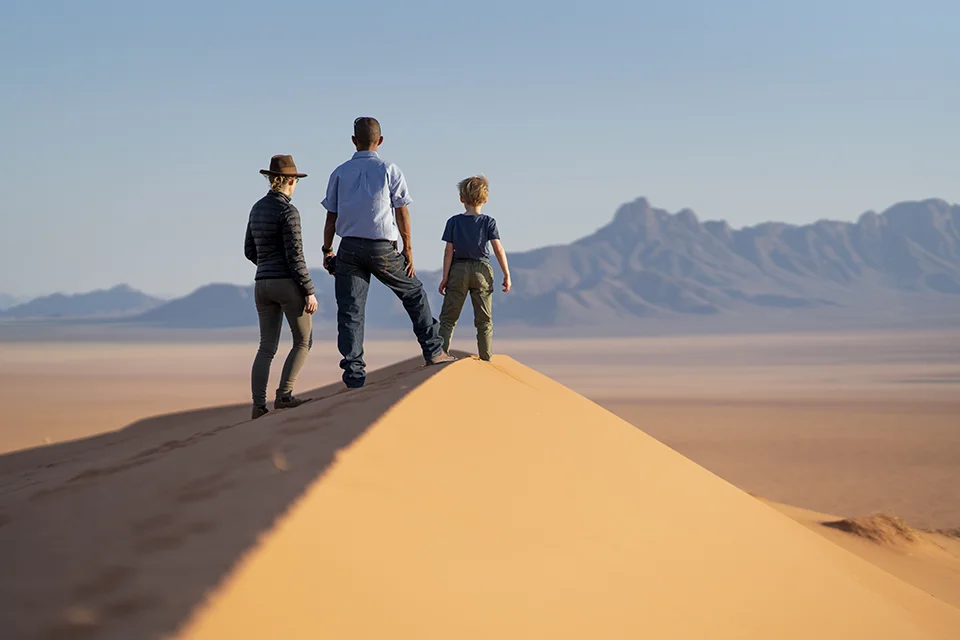 Family exploring the desert dunes near Kwessi Dunes in Namibia
