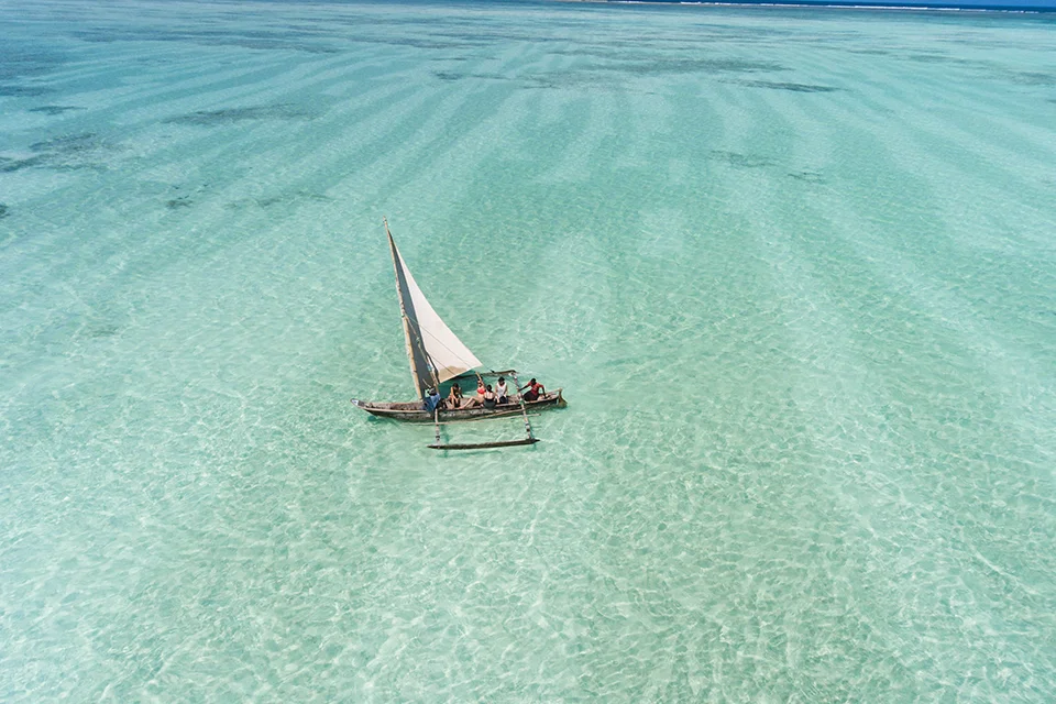 Traditional dhow sailing across the shallow turquoise waters off Zanzibar, Tanzania