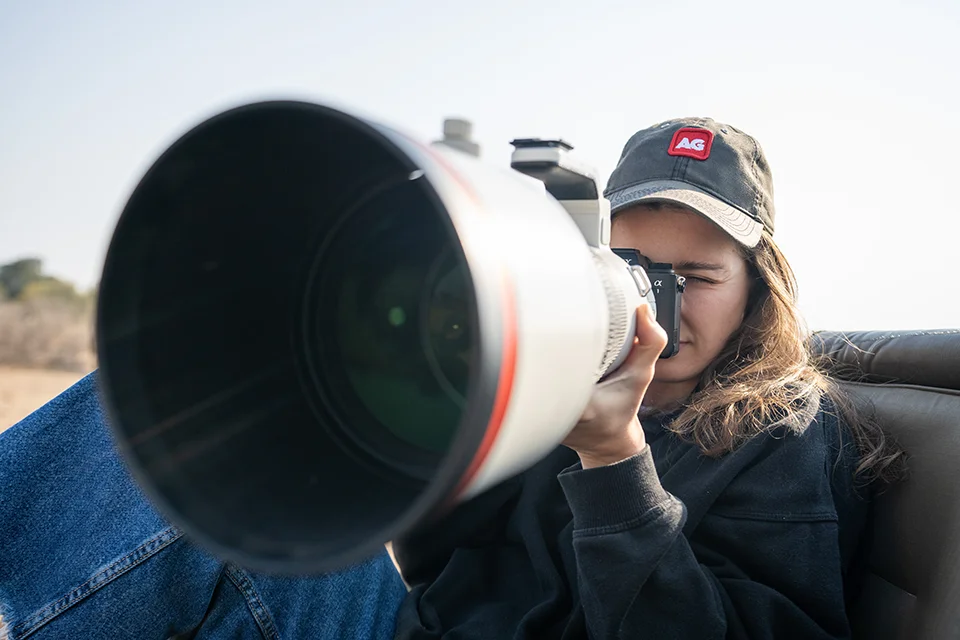 Traveller using a camera with a telephoto lens to photograph wildlife during a safari