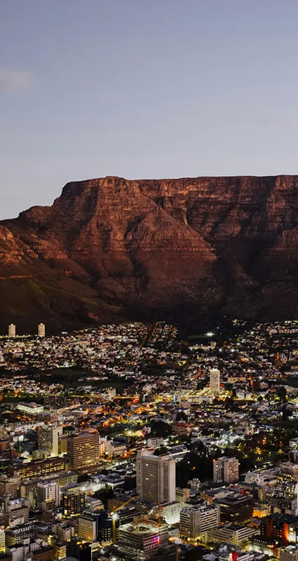 Cape Town city lights beneath Table Mountain at dusk, South Africa