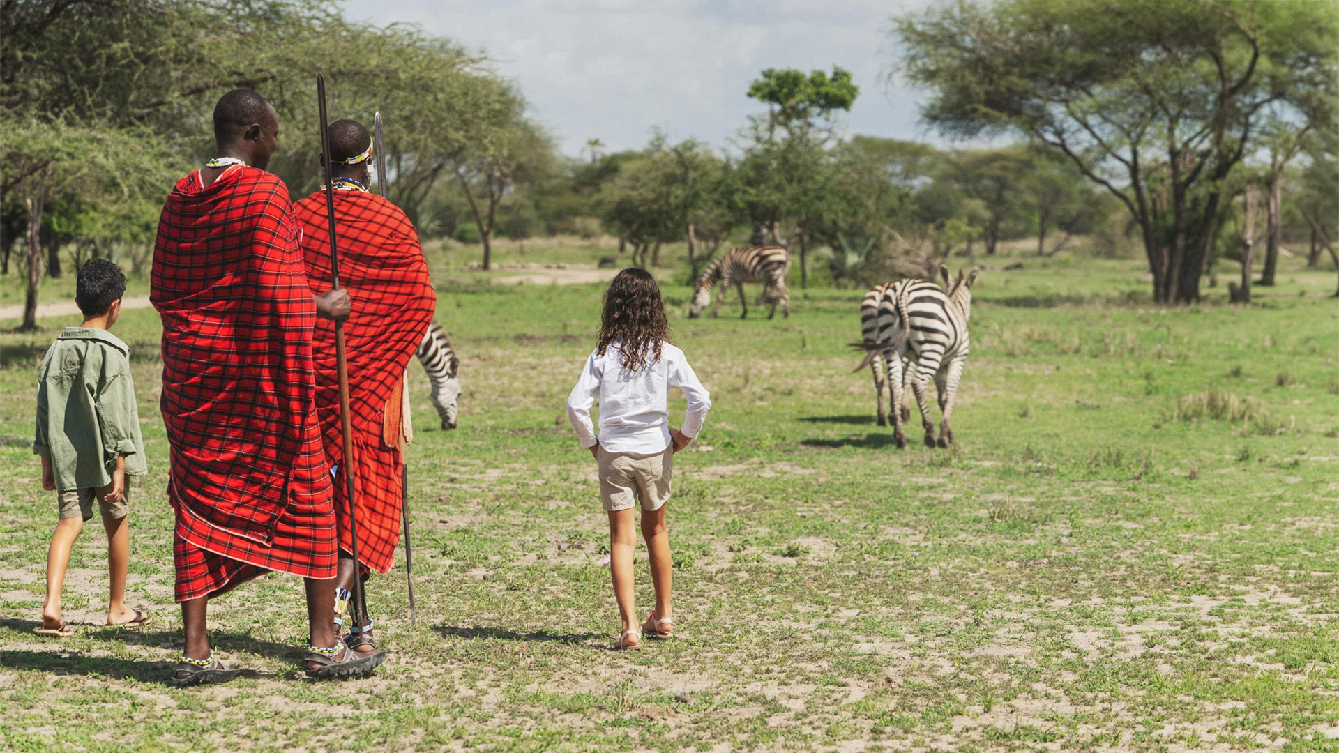 Children on a walking safari with Maasai guides watching zebras near Little Chem Chem Camp, Tanzania