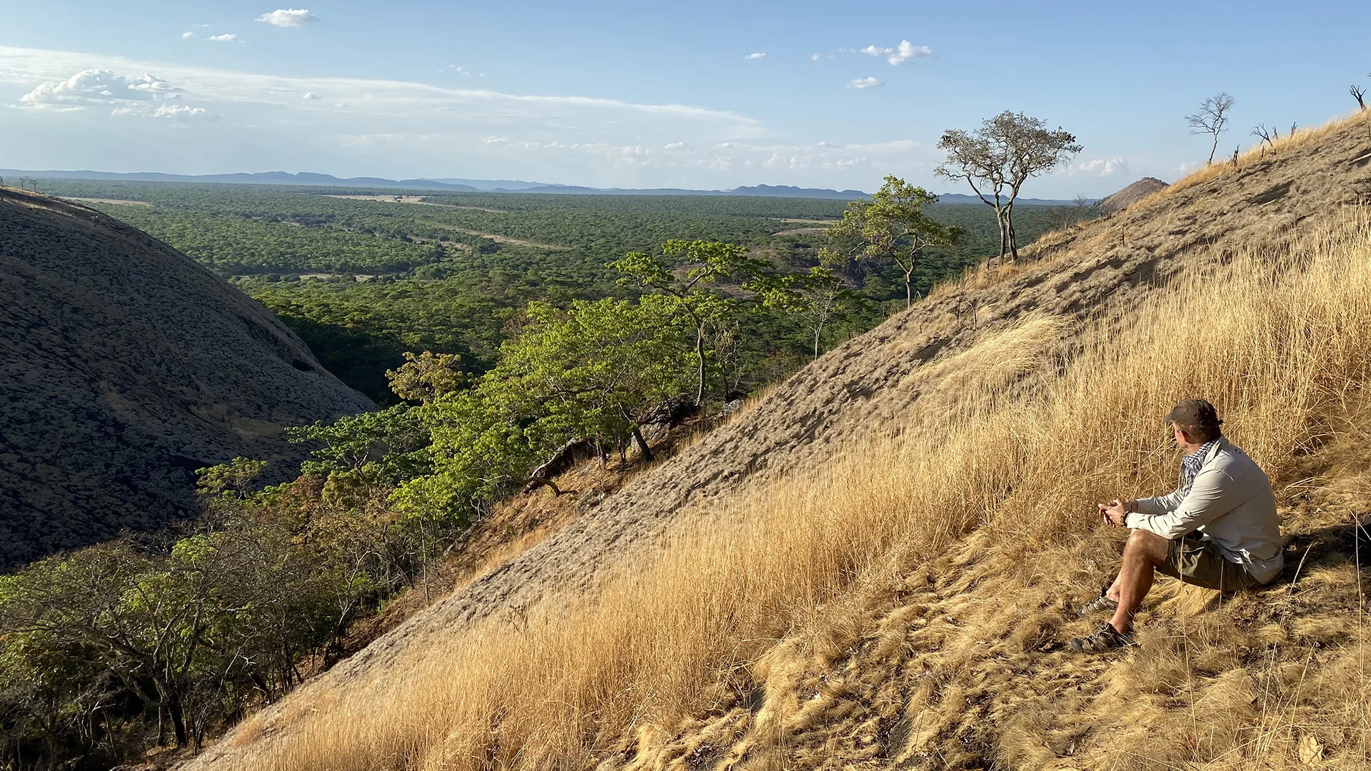 Guest resting on a rocky hillside overlooking the remote wilderness of Matobo National Park, Zimbabwe