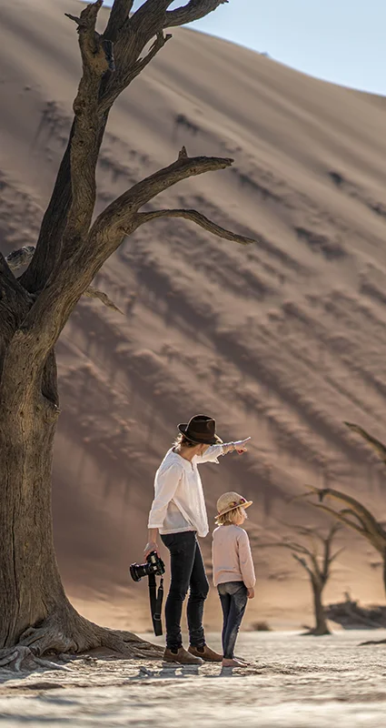 Adult and child exploring the dead trees and towering dunes of Deadvlei, Namibia