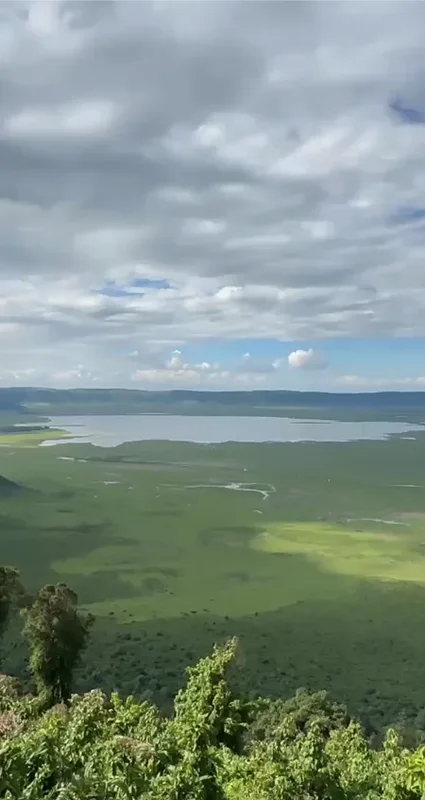 Panoramic view across the lush Ngorongoro Crater floor and lake, surrounded by steep crater walls in Tanzania