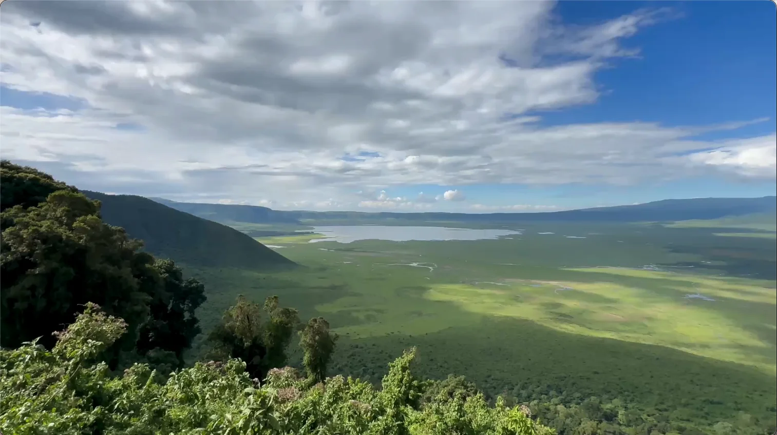 Panoramic view across the lush Ngorongoro Crater floor and lake, surrounded by steep crater walls in Tanzania