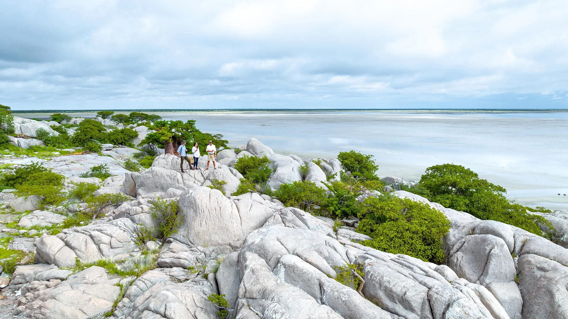 Guests exploring rocky outcrops overlooking a vast salt pan landscape