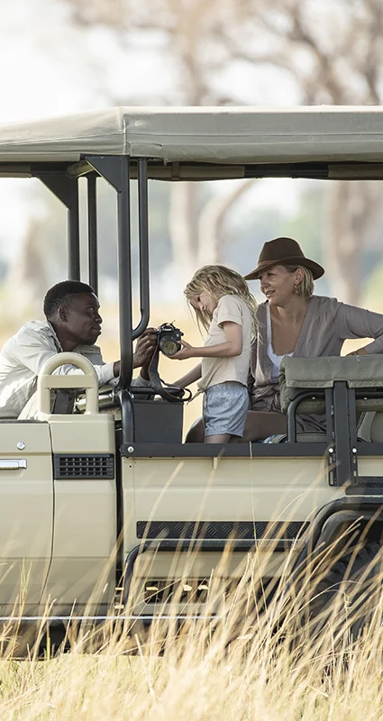 Family reviewing wildlife photos with their guide during a safari game drive at Shinde Camp, Botswana