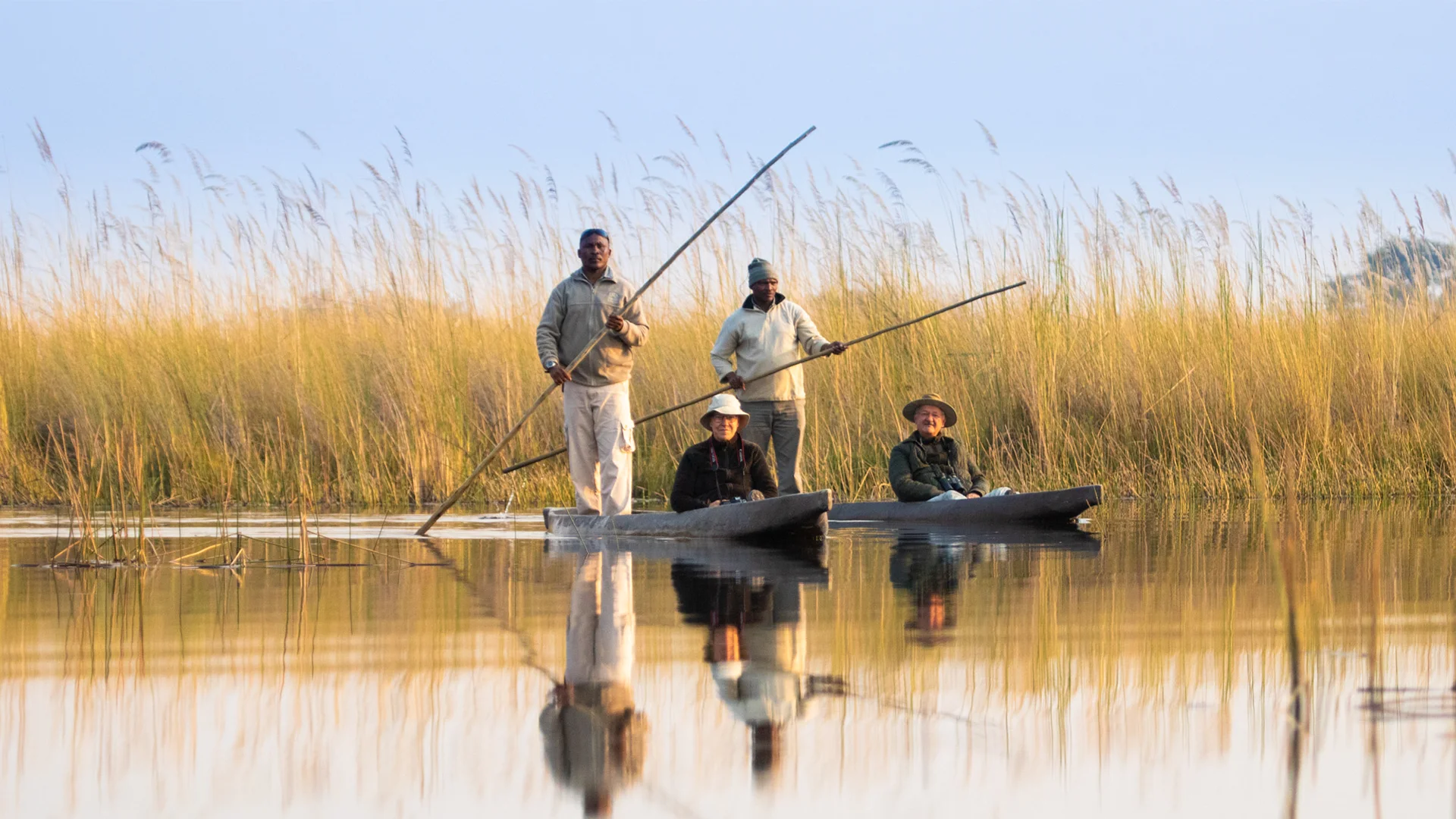 Guests enjoying a traditional mokoro excursion through the reed-lined waterways of the Okavango Delta