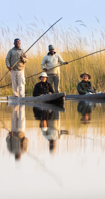 Guests enjoying a traditional mokoro excursion through the reed-lined waterways of the Okavango Delta