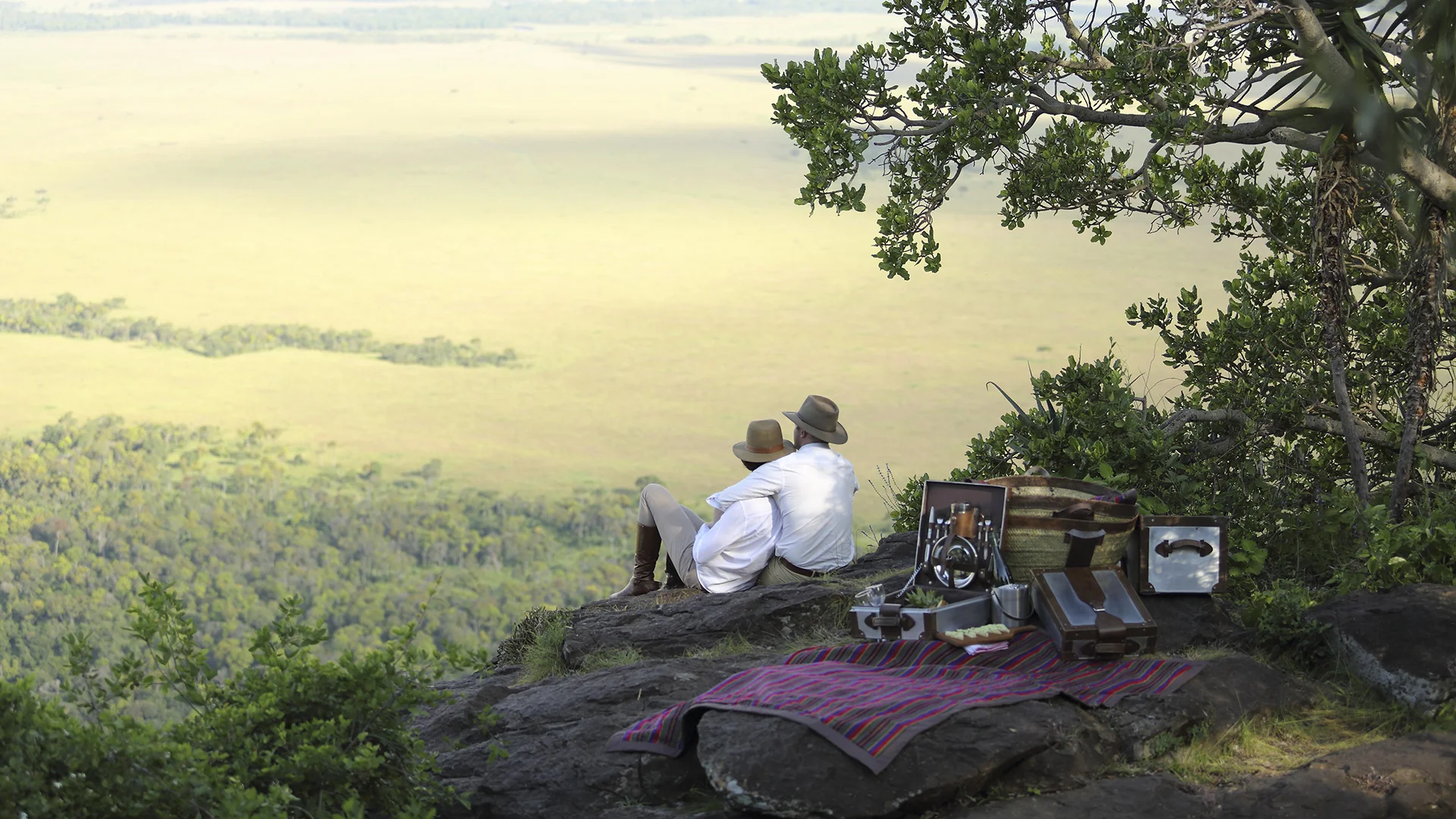 Couple enjoying a private picnic overlooking the Maasai Mara from the Out of Africa kopje at Angama Mara, Kenya