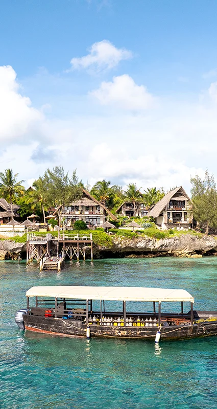 Sunshine Marine Lodge overlooking turquoise waters off Zanzibar, Tanzania, with a traditional dhow in the foreground