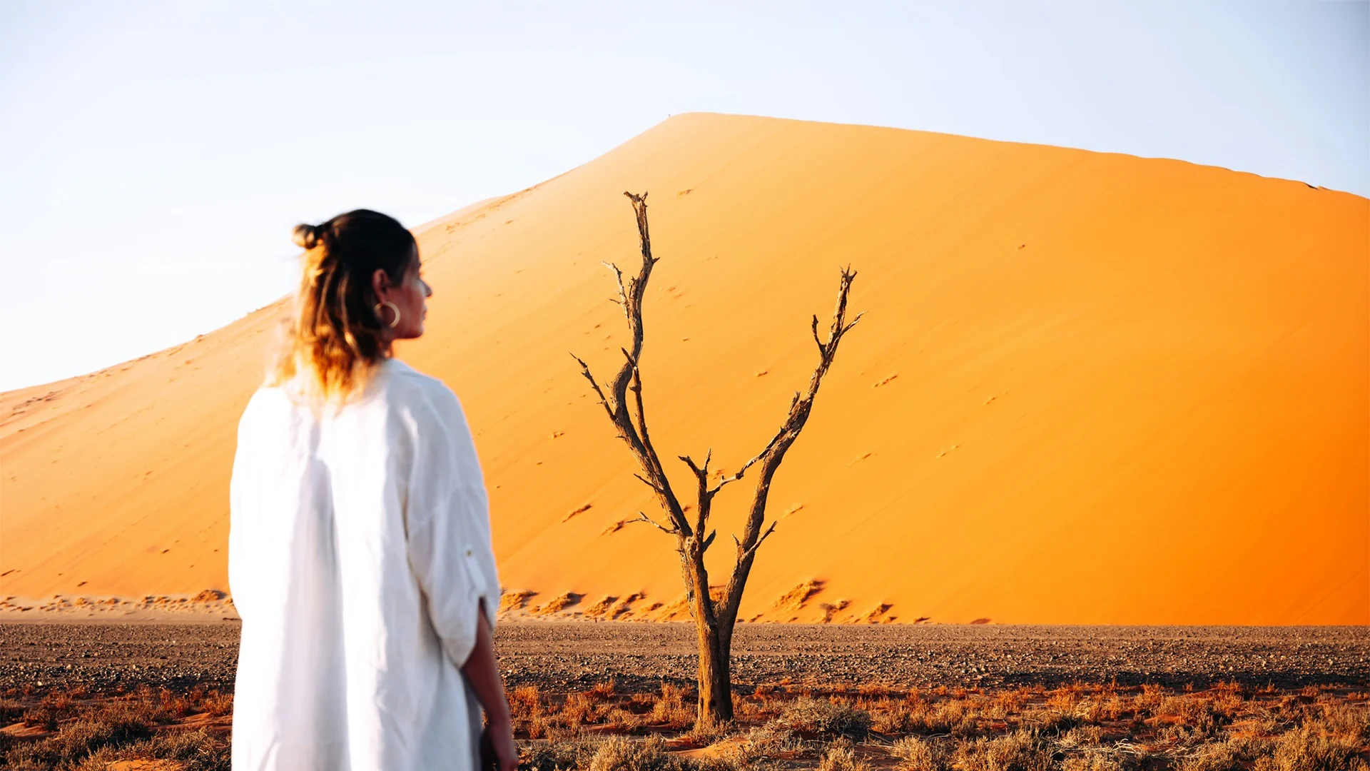 Woman admiring the towering orange sand dunes near Wilderness Kulala Desert Lodge in Sossusvlei, Namibia