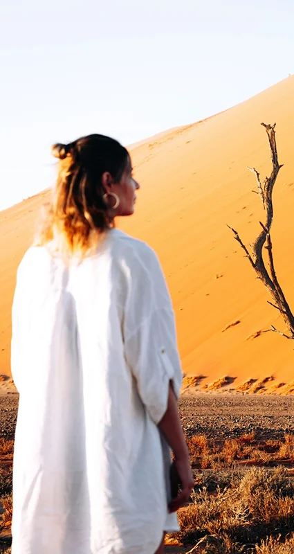 Woman admiring the towering orange sand dunes near Wilderness Kulala Desert Lodge in Sossusvlei, Namibia