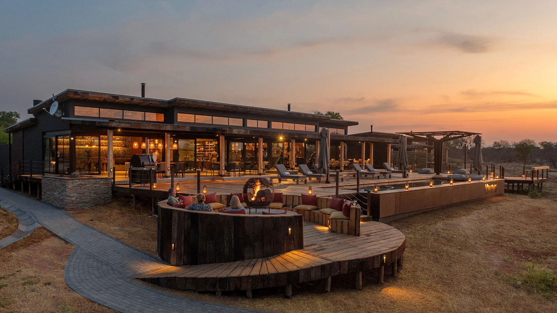Guests relaxing around a fire pit at Ximuwu Lodge at sunset